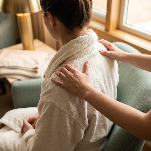 Two hands kneading a seated client’s shoulders
